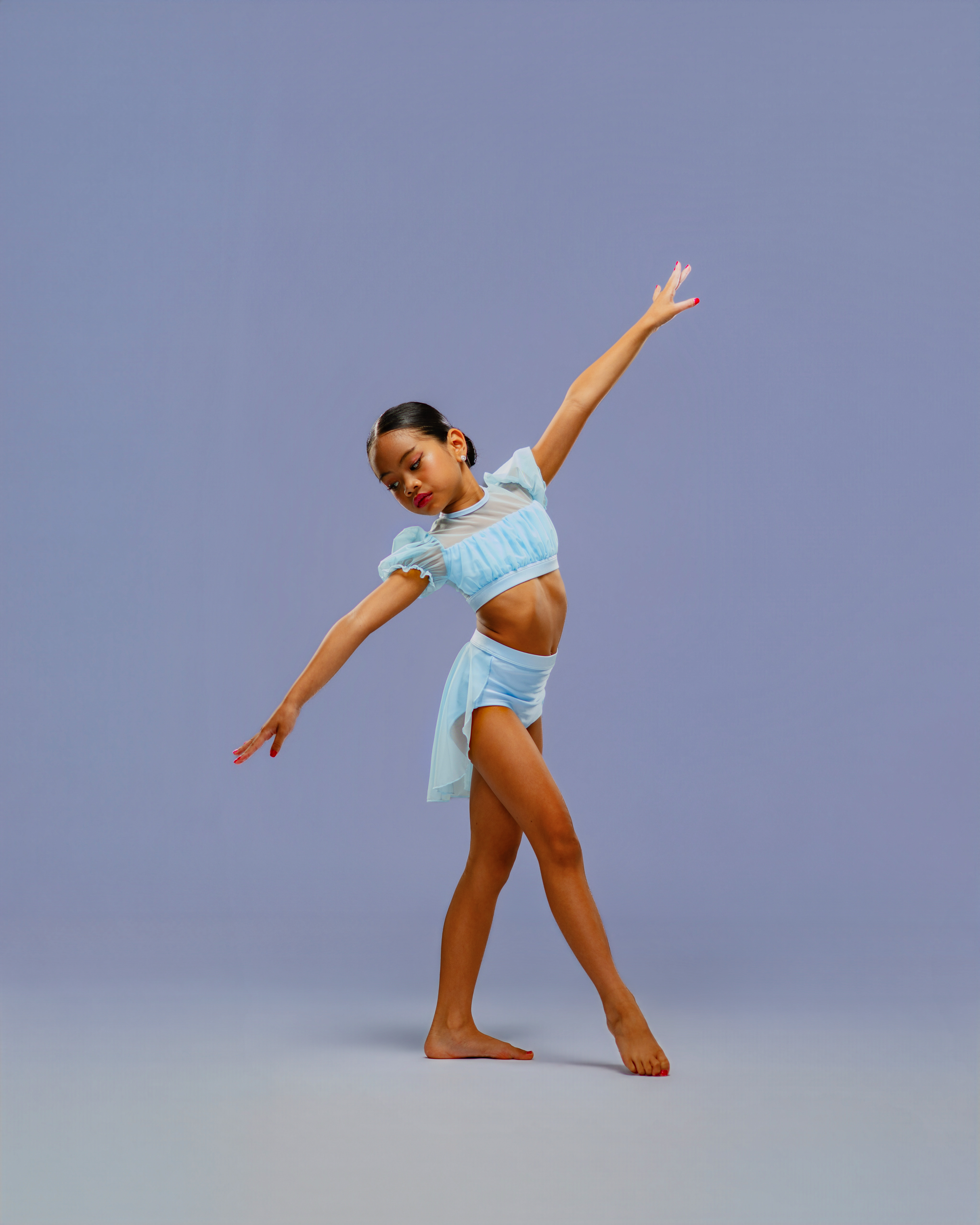 Pichara Luong captured in expressive movement against a blue studio backdrop